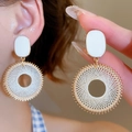 Primo piano di orecchini a cuore asimmetrici bianchi con dettagli dorati intrecciati - Stile Intrecciato Tondo / Oro Bianco Clip