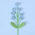 Detailansicht handgehäkelter blauer Vergissmeinnicht-Blumen mit grünen Wollblättern - Blau