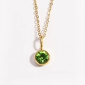 Macro detail of a golden necklace featuring a polished round green gemstone pendant - August Peridot Green