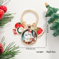 Détail d'un porte-clés de Noël avec Père Noël, village enneigé et clochette rouge - Cloche de Noël