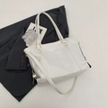 White faux leather tote bag with gold ring hardware and crossbody strap on gray background - White