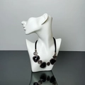 Detail shot of a bohemian multi-layered necklace with black gems on a white mannequin torso - White