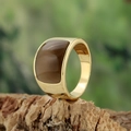 Golden stainless steel band ring with brown cat eye stone on natural wood background - Gold Coffee