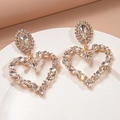 Orecchini a cuore dorati con strass marquise presentati su un piatto bianco circolare - Ago d'argento / Bianco