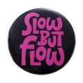Round tinplate badge featuring SLOW BUT FLOW text in pink on a black background - SLOW BUT FLOW