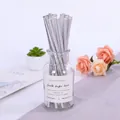 Silver party paper straws in a glass jar with a white label on a grey background - Silver Straw