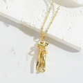 Gros plan d'un collier doré avec pendentif minimaliste de deux figurines enlacées - Câlin Doré