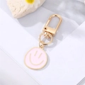 Detail of light pink round keychain with golden minimalist smile face charm on stone base - Light Pink