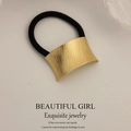 Minimalist black hair tie featuring a golden brushed metal curved accessory for ponytail - Curved Rotating Stripe Gold