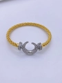 Detalle de brazalete trenzado dorado con cierre de herradura y cristales brillantes - Oro de 18K / Oro + Plata