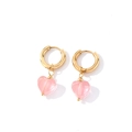 Détail de pendentifs en forme de cœur rose sur des boucles d'oreilles dorées - Or + Rose