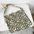 Flat lay of beige canvas tote bag with green floral pattern on a white desk surface - Green Leaf Floral
