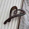 Detail of dark brown heart-shaped hair claw clip on neutral textured fabric background - Transparent Tea