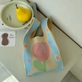 Detailed close-up of a knitted tote bag featuring pink tulip patterns and blue wavy edges - Tulips In Light Blue