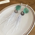 Detail of long feather tassel earrings with green resin drops on a ceramic tray - Silver Pin - Green - Grey Feather