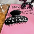 Detail of black acetate hair claw clip featuring sparkling rhinestone star and moon motifs - 9cm / Black