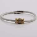 Detail of white cord bracelet featuring a gold crown-edge barrel bead set with cubic zirconia - White