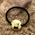 Dettaglio di un elastico per capelli nero con ciondolo circolare d'oro su pietre naturali - Tondo Dorato
