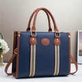 Navy blue faux leather tote bag with brown handles and a central striped webbing detail - Blue