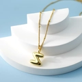Golden bubble letter S pendant necklace with beaded chain on a tiered display - Letter Z(Z)