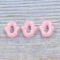 Close-up of three pink Hamsa opal resin charms with iridescent effect on wood surface - Pink