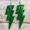 Macro shot of green glitter lightning earrings with silver hooks on stone background - Glitter Green