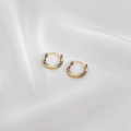 Detailed macro view of gold-plated hoop earrings with black and white enamel pattern - Black+White
