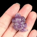 Miniature amethyst tortoise carving held in hand with natural purple crystal texture - Amethyst