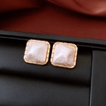 Macro shot of square gold earrings with white textured resin inlays on a black display - Real Gold Plated Beige Square (Silver Pin)