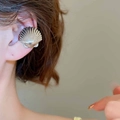 Dettaglio ravvicinato di un ear cuff a forma di conchiglia dorata con texture metallica fine - Clip per orecchio singolo / Argento