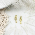 Detailed view of two gold key charms featuring zircon inlays and hollow mesh patterns - Key
