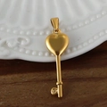 Détail macro d'un pendentif clé plaqué or 24 carats avec un design de cœur sur le dessus - Clé du Cœur / Or