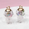 Detail view of two transparent astronaut pendants with colorful rings and gold metal hooks - Astronaut / Colorful