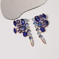 Detail of luxury teardrop tassel earrings with blue and purple crystals and gold metal - Blue