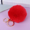 Macro detail of a fluffy red pompom keychain featuring a polished golden metal clasp - Red