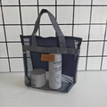 Dettaglio borsa da spiaggia in rete grigia con manico su sfondo piastrellato nero - Blu navy