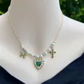 Detail van gouden ketting met parels, groen zirkoonhart en strik gedragen door een model - Stijl 1 - Groene Hangers