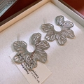 Macro shot of silver hollow-out flower stud earrings on an elegant textured jewelry box - Silver (Silver Pin)