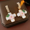 Primer plano de pendientes vintage de flores con perlas y cristales en joyero elegante - Pin de Plata Blanco Verde