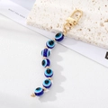 Detail of blue evil eye bead keychain with gold hardware on a textured stone - Blue