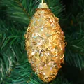 Detail of 11cm gold sequined oval Christmas ball ornament hanging on a pine tree branch - Gold