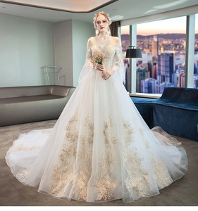 Detail of elegant off-shoulder lace sleeves and heavy gold floral embroidery on ivory gown