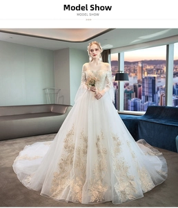 Detail of off-the-shoulder wedding dress with gold floral embroidery and long lace sleeves