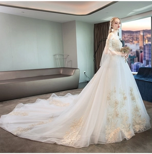 Detailed close-up of intricate gold floral lace embroidery on an ivory off-shoulder wedding gown
