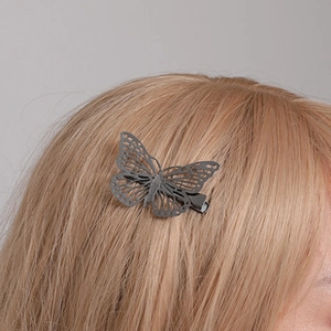 Detail of dark grey hollow butterfly hair clip with bionic wing texture on blonde hair