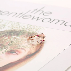 Anello floreale in oro rosa con pietre rosa e perle su sfondo di una rivista