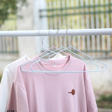Close-up of blue and pink plastic-coated metal hangers with non-slip grooves on a rod