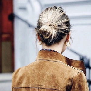 Minimalist gold hoop earrings paired with a brown suede jacket in a stylish street view
