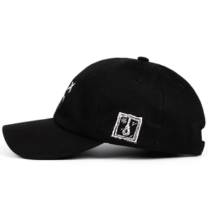 Black cotton baseball cap with white sad boy embroidery in a side profile view