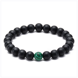 Detail view of 8mm matte black agate beads and green malachite stone on elastic bracelet